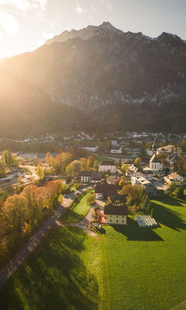Luftaufnahme von St. Leonhard im Salzburger Land, mit Hotel, Gasthof Schorn und Bergen im Sonnenuntergang.
