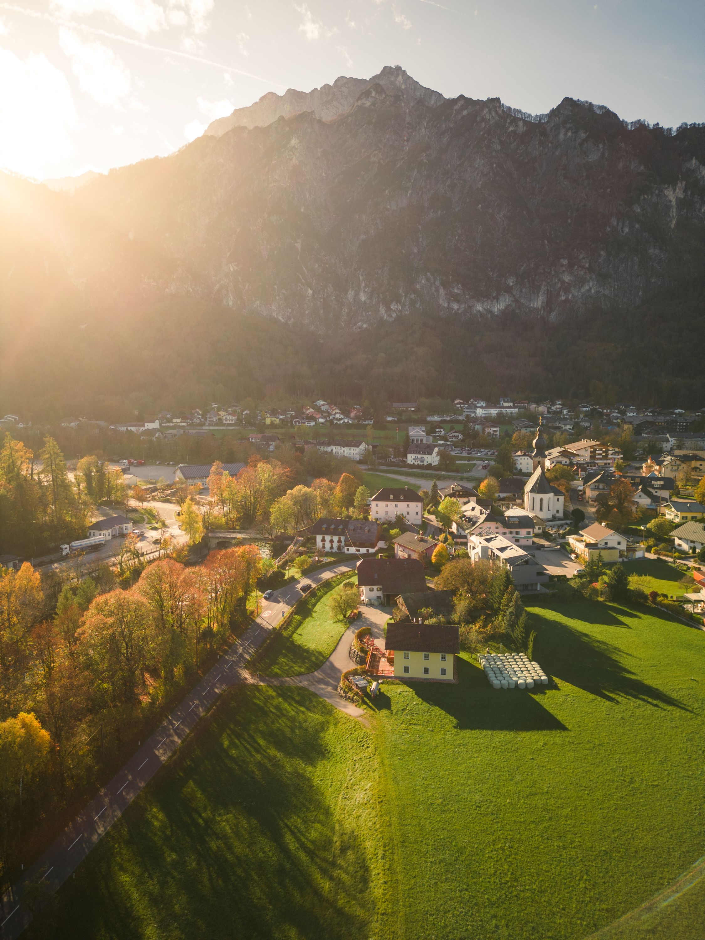 Luftaufnahme von St. Leonhard im Salzburger Land, mit Hotel, Gasthof Schorn und Bergen im Sonnenuntergang.